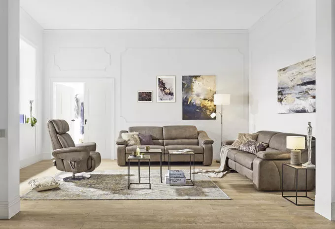 klassische Wohnzimmermöbel mit einem Sessel und zwei Sofas in Erdtönen kombiniert mit dezenten fliederfarbenen Akzenten in der Dekoration