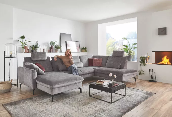 Frau sitzt auf grauer Couch in U-Form
