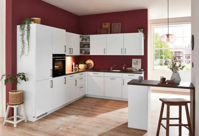 weiße klassische Küche mit Arbeitsplatte aus dunklem Holz und roter Wandfarbe